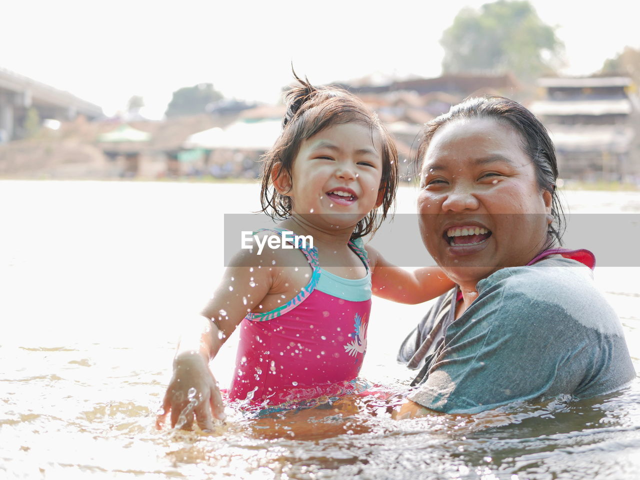 Portrait of smiling mother and daughter swimming in lake