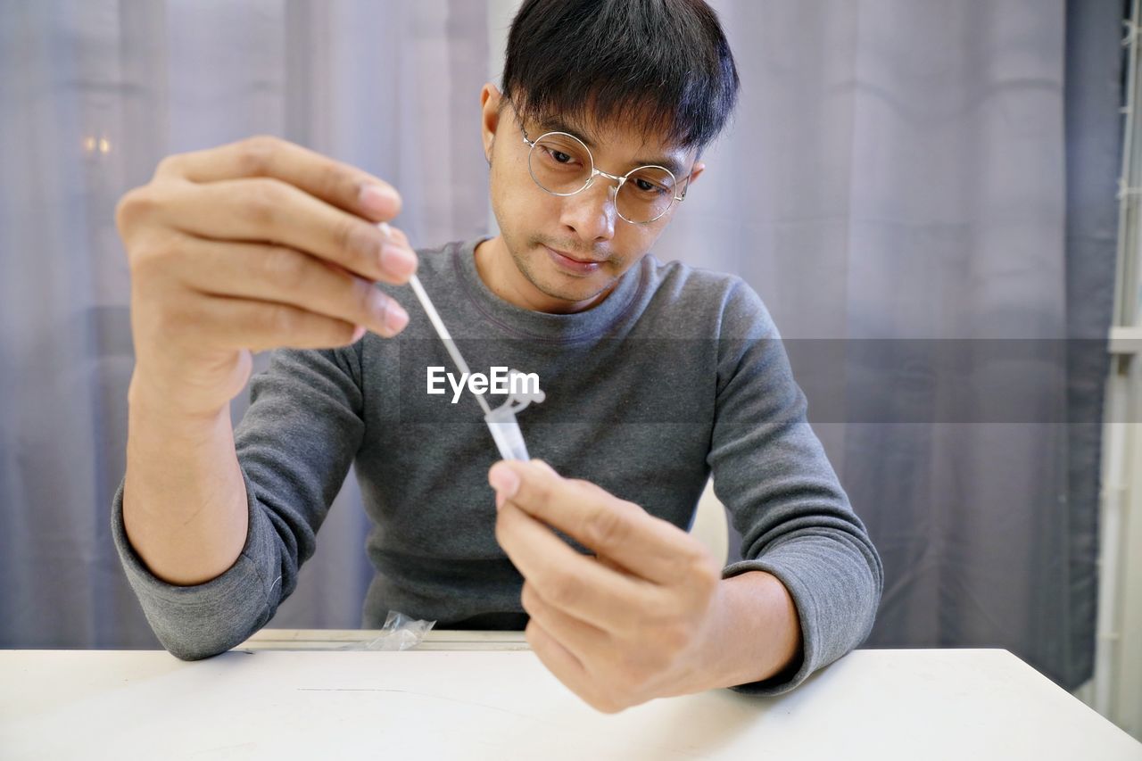 Man uses cotton swab to test for covid-19 insert a reagent bottle 