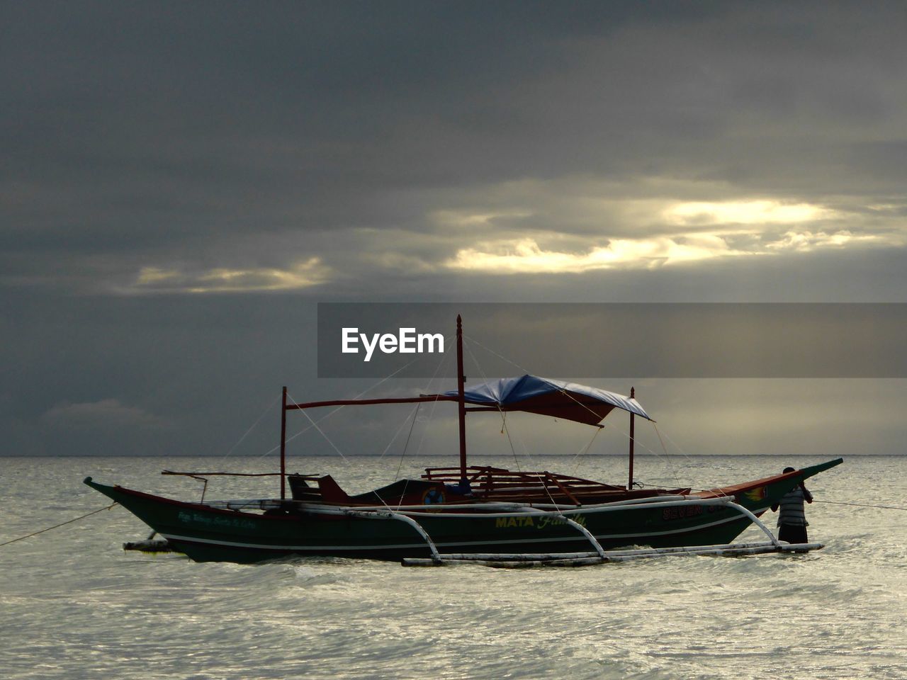 BOAT MOORED AT SEA AGAINST SKY