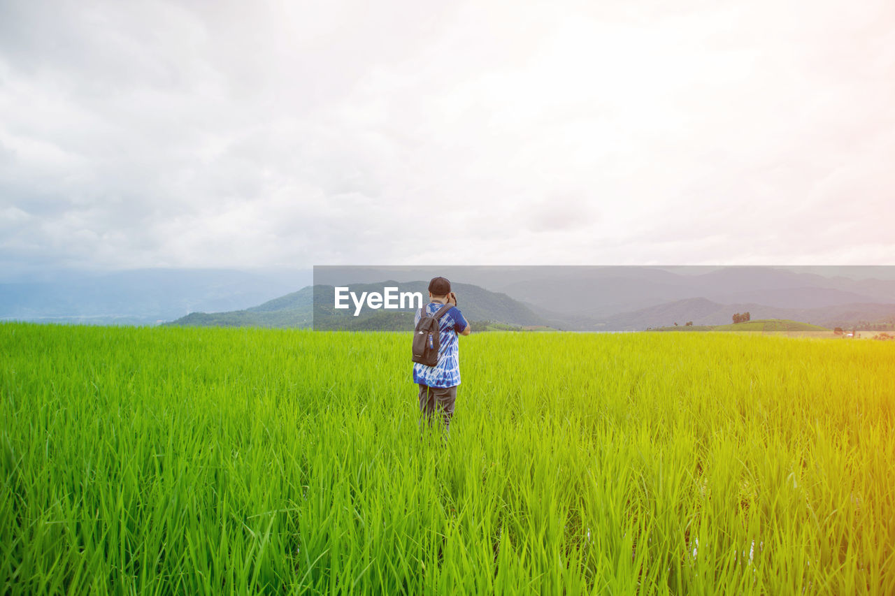 Woman standing on grassy field against sky