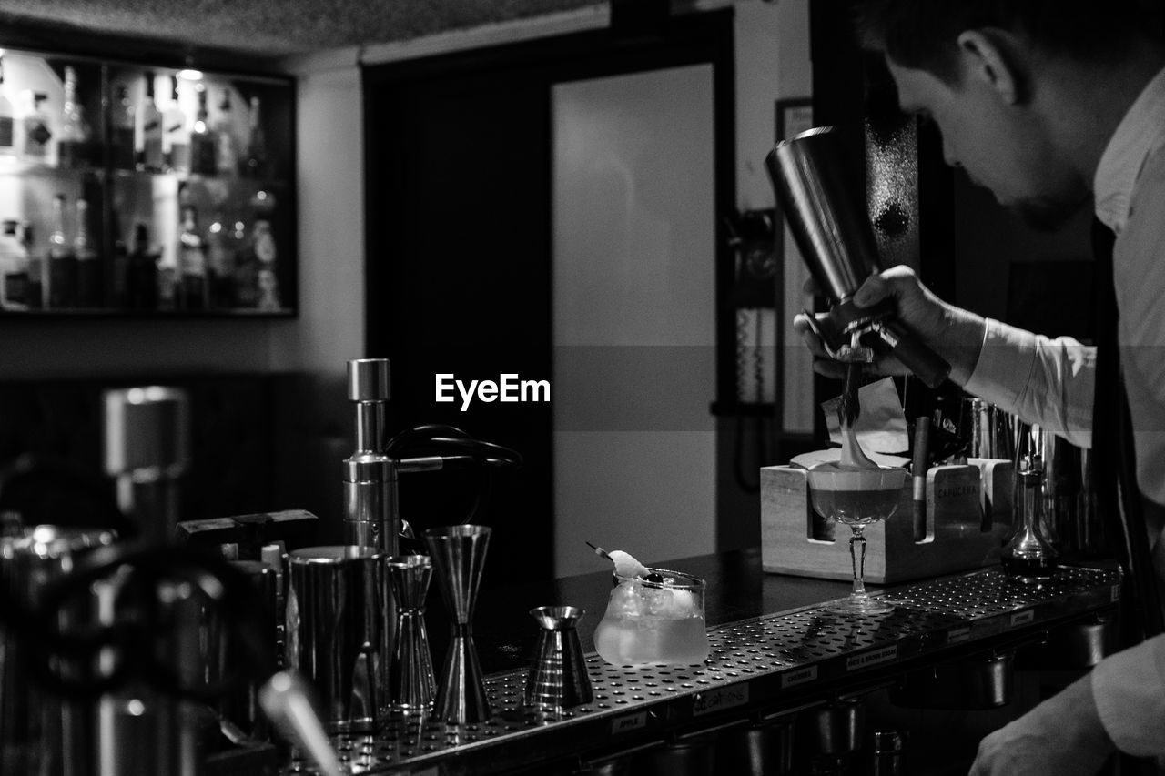 MIDSECTION OF MAN PREPARING FOOD IN BAR