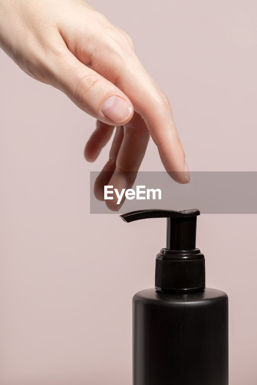 A womans hand and black dispenser with a cream. mockup. high quality photo