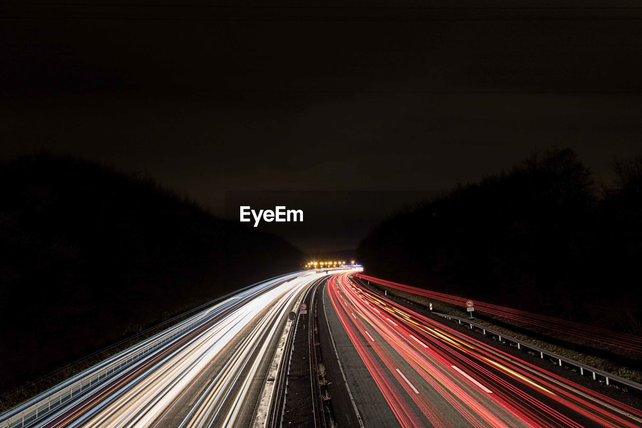 Light trails on road against clear sky at night