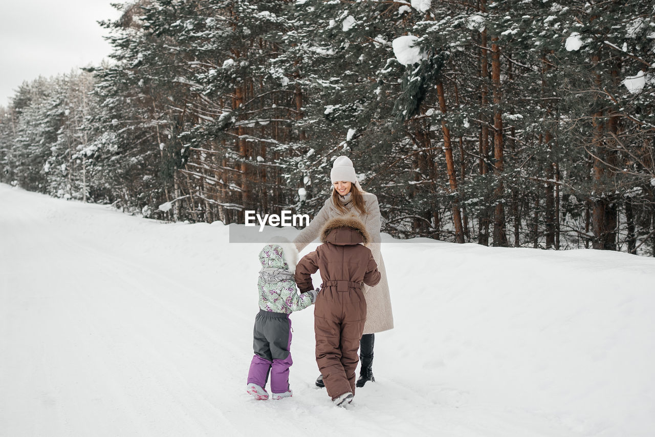 Mother with two daughters walks in a snowy forest on her day off. high quality photo
