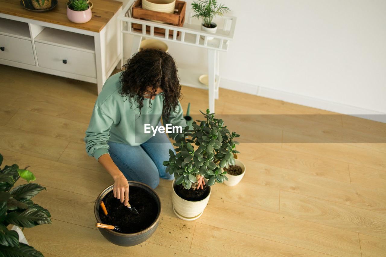 high angle view of girl playing with potted plant on floor at home