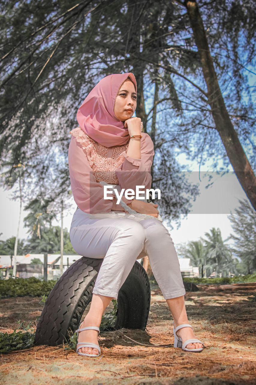 Full length of young woman sitting in park