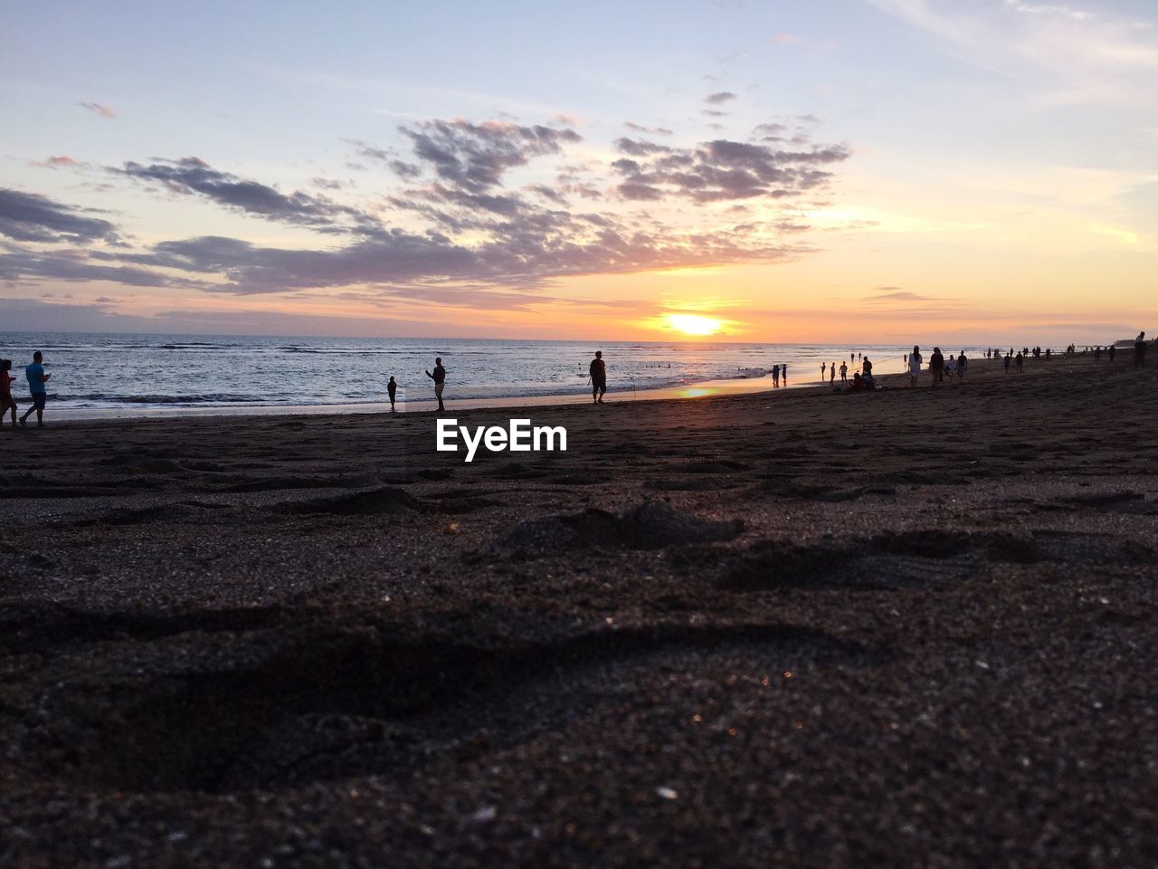 People walking on beach at sunset