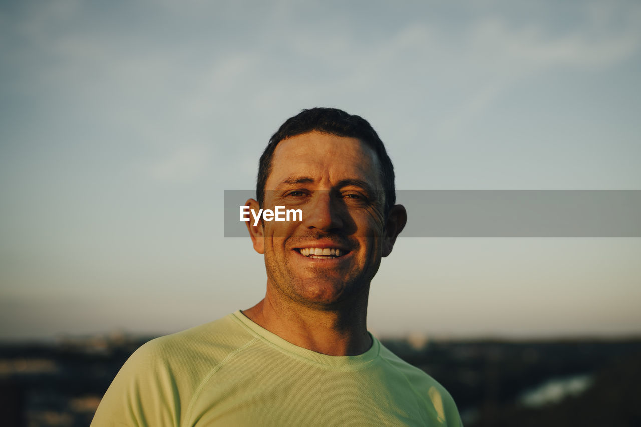 Portrait of smiling sportsman against sky during sunset