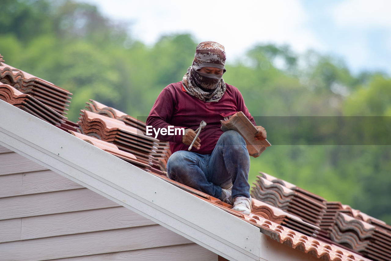 LOW SECTION OF MAN SITTING ON ROOF