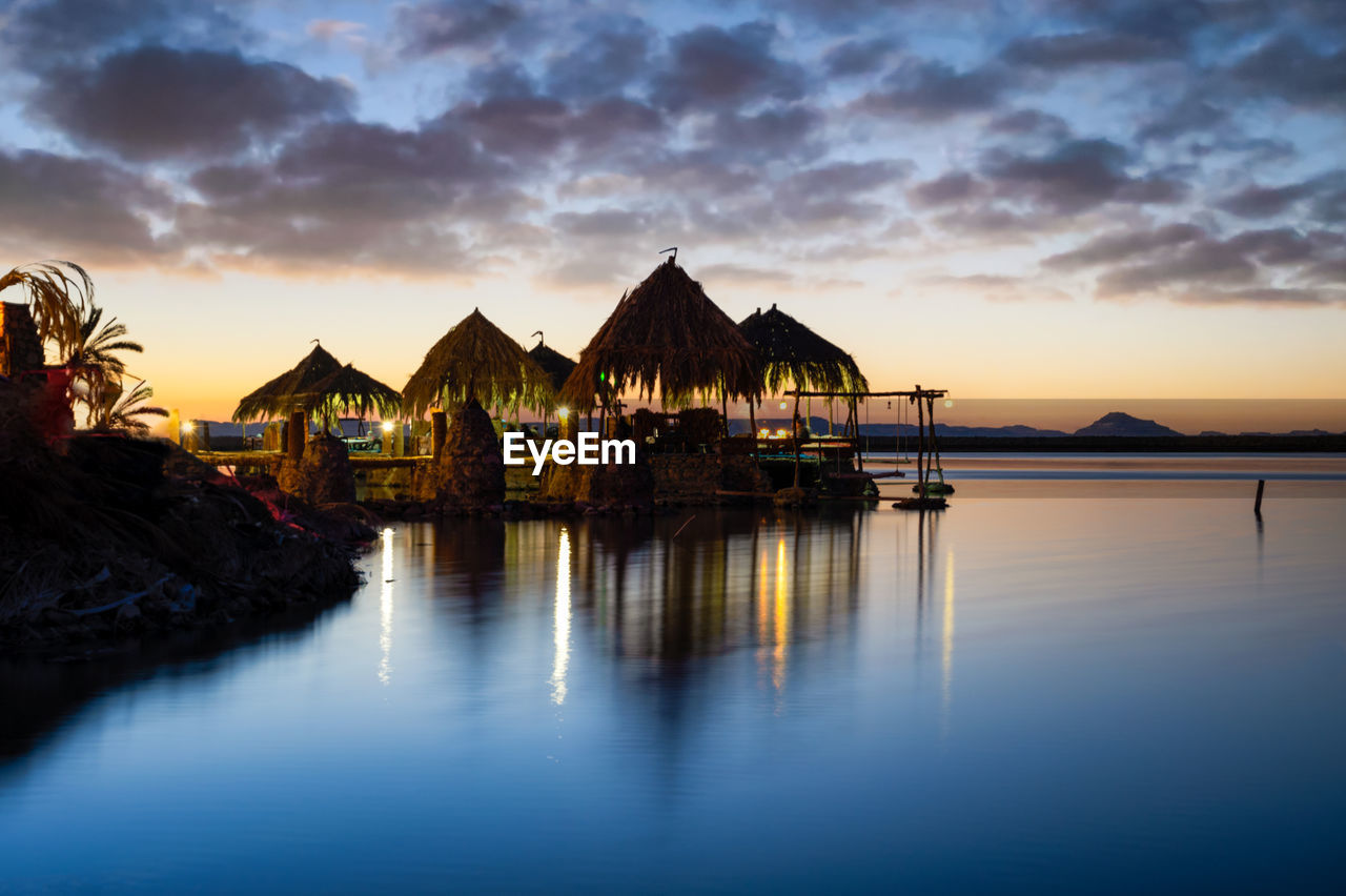 BUILT STRUCTURE ON SEA AGAINST SKY DURING SUNSET
