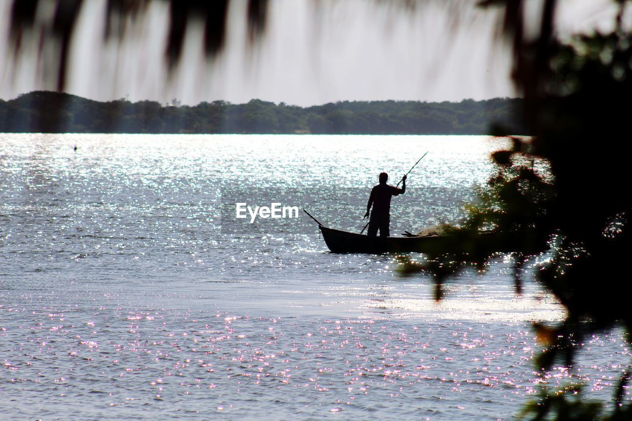 SILHOUETTE MAN IN SEA AGAINST BOAT