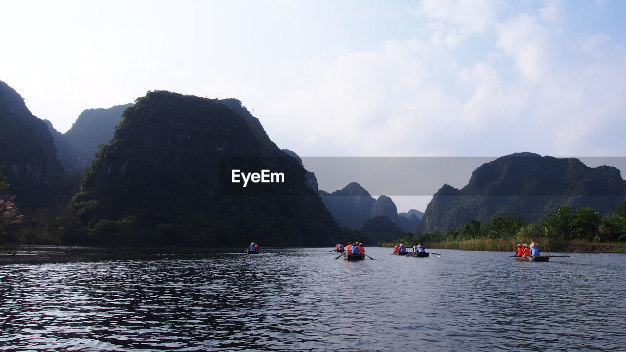 Boats in sea with mountain range in background