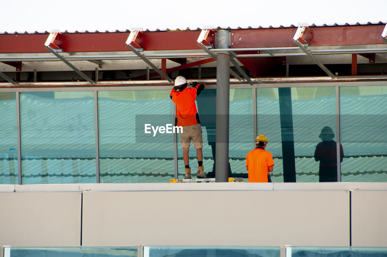 REAR VIEW OF WORKER WORKING ON WATER