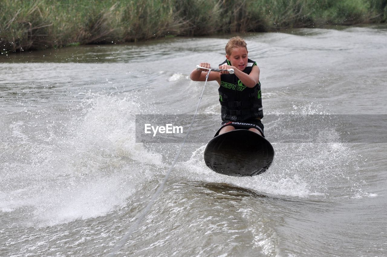 Boy riding kneeboard on river - water sports