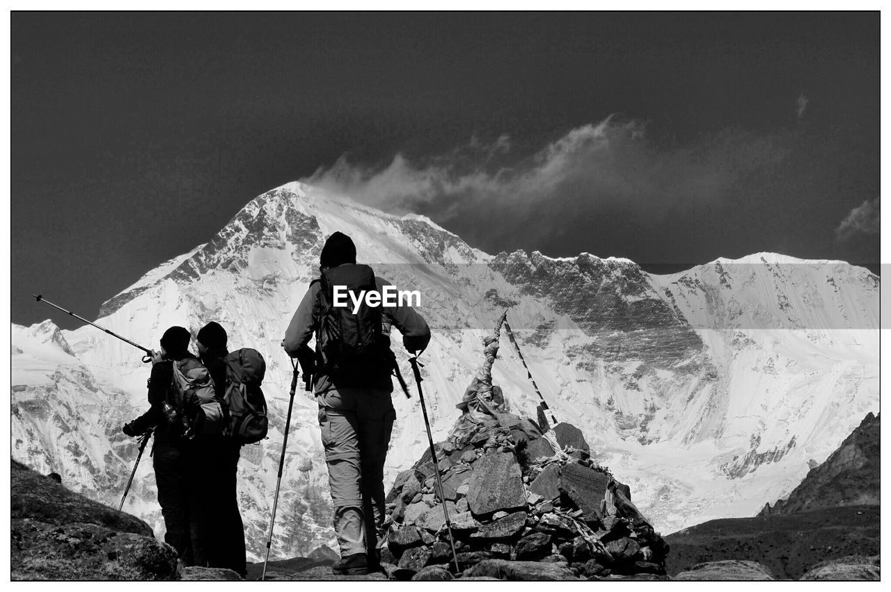 Rear view of hikers climbing against mountain