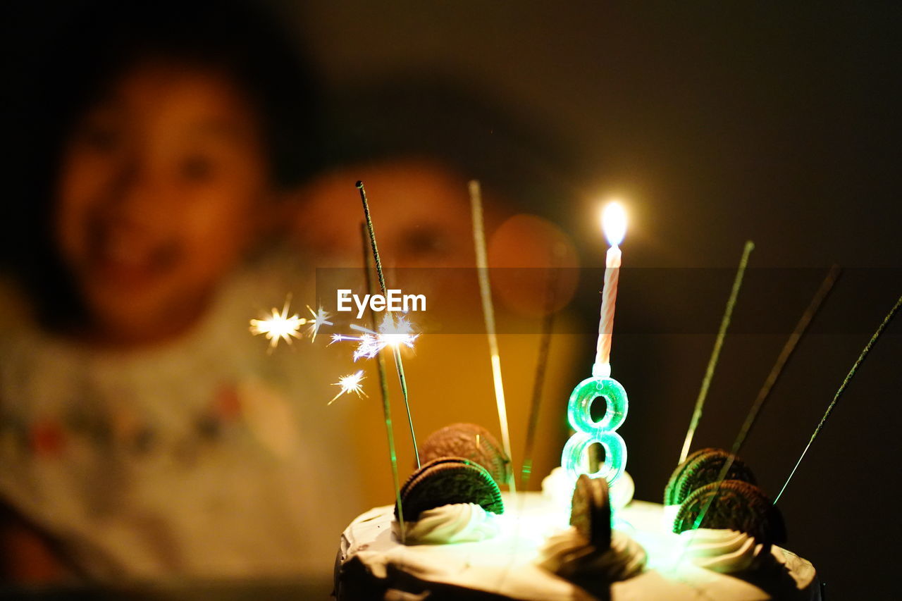 Close-up of birthday cake with candles in darkroom