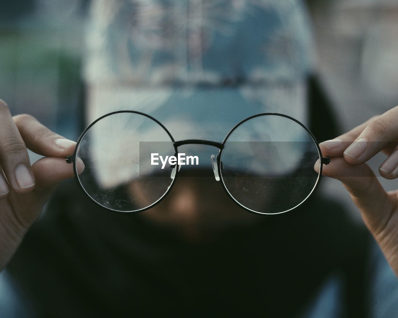 Close-up of hand holding eyeglasses on glass