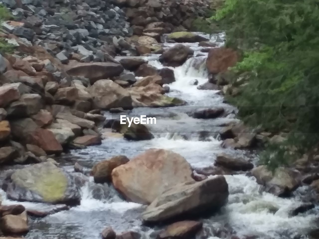 SCENIC VIEW OF WATERFALL AT RIVERBANK