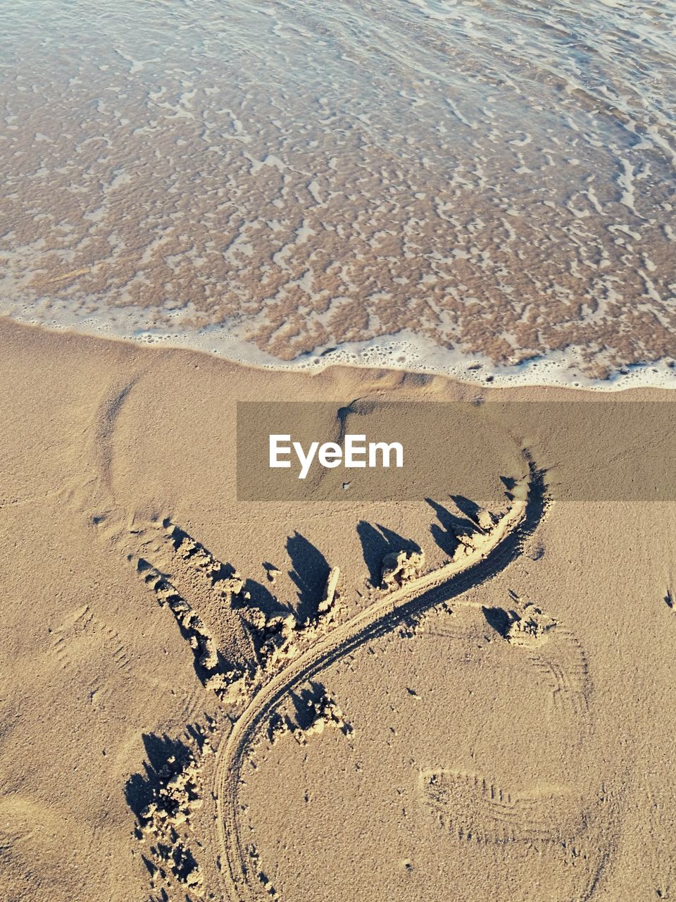 HIGH ANGLE VIEW OF FOOTPRINTS ON SAND AT SHORE