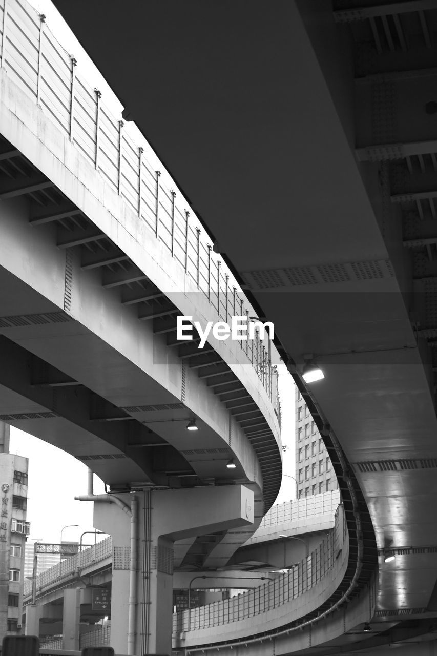 Low angle view of bridge amidst buildings against sky