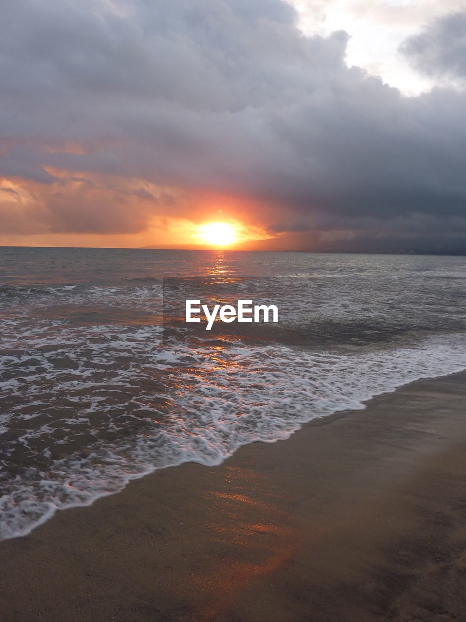 Scenic view of sea against cloudy sky during sunset