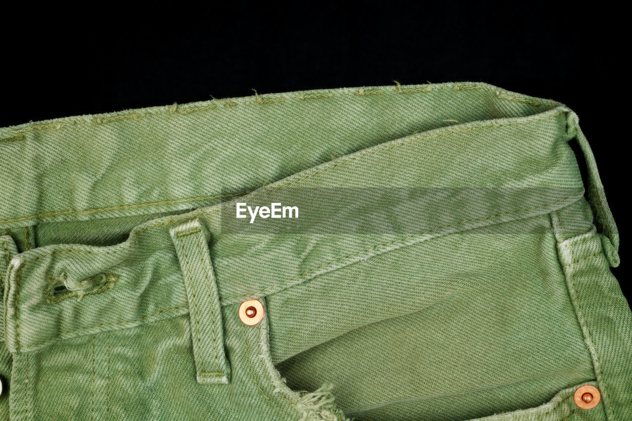 Close-up of green jeans on black background