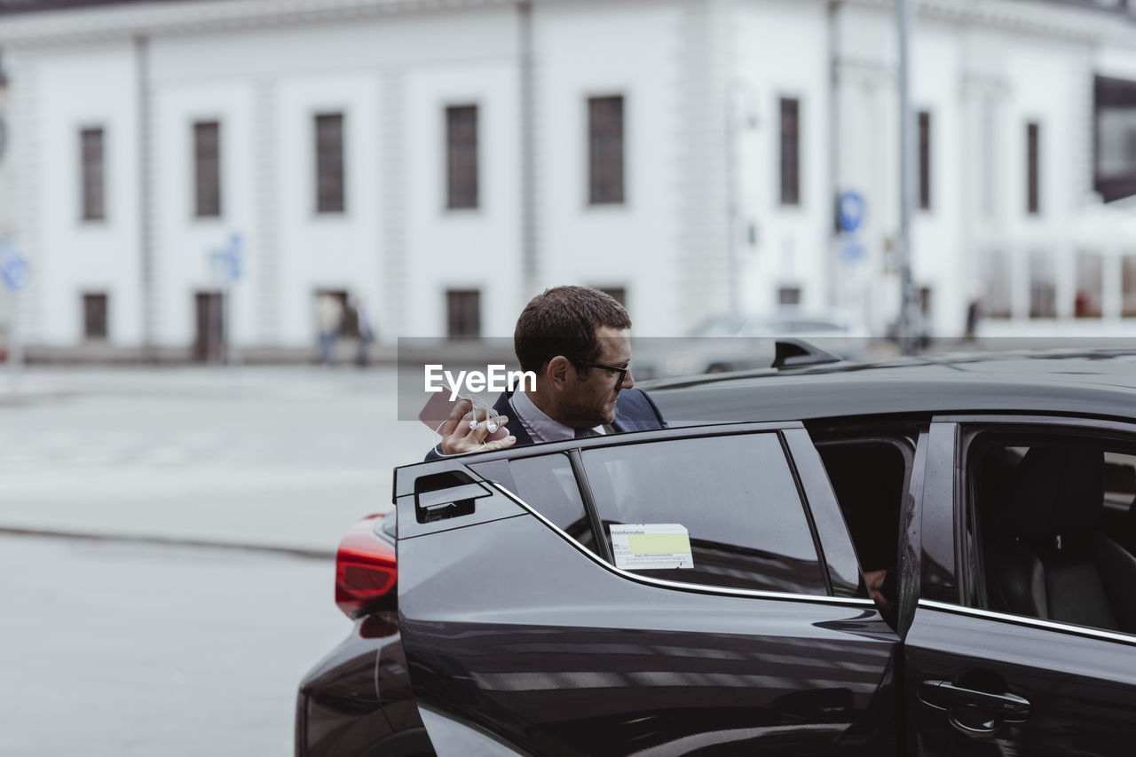 Businessman with smart phone sitting in car