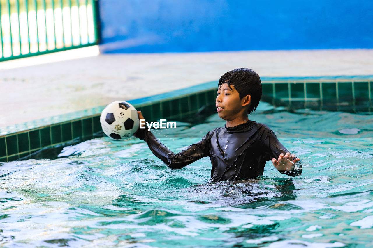 Full length of a boy with ball in swimming pool