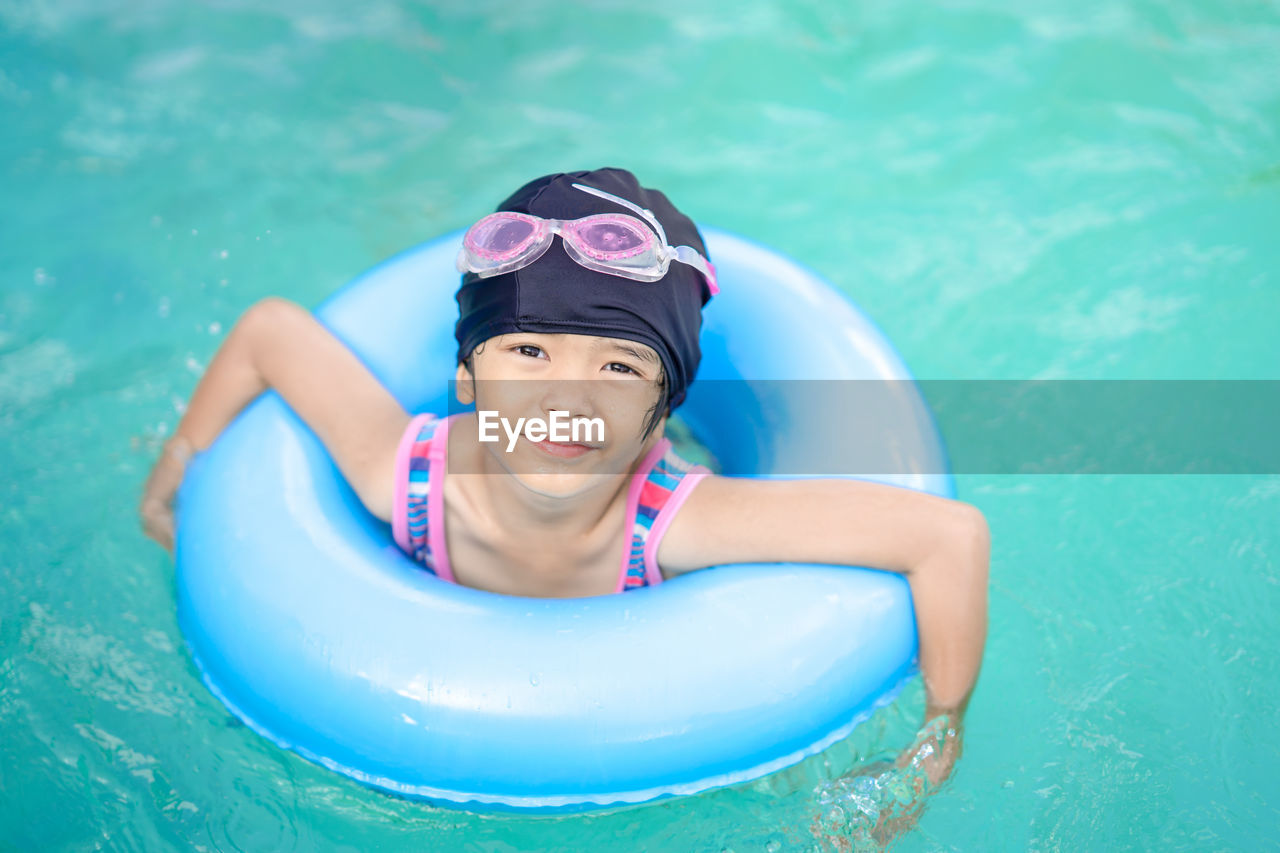 Portrait of smiling girl on inflatable ring in swimming pool