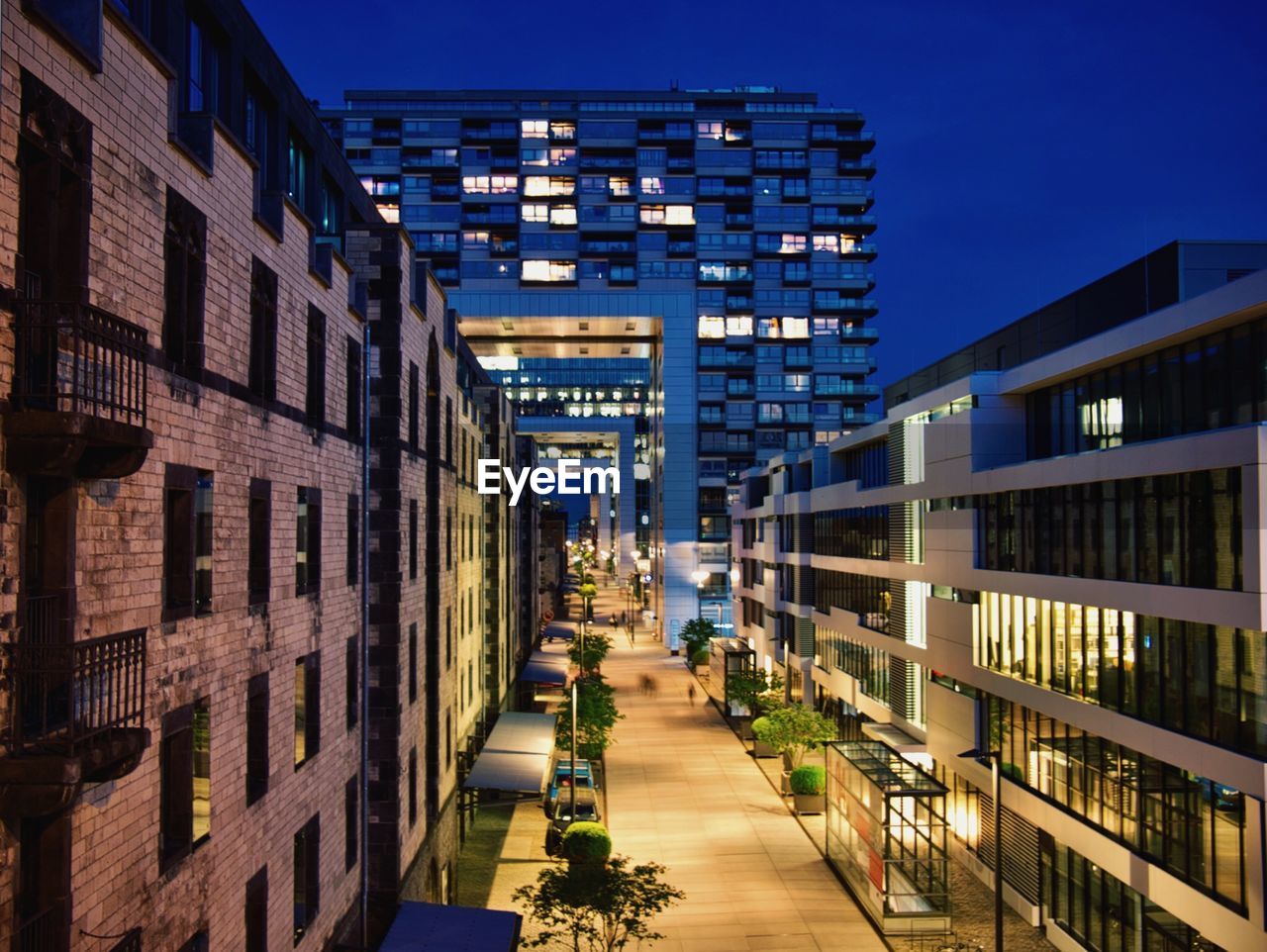 STREET AMIDST BUILDINGS AGAINST SKY AT NIGHT