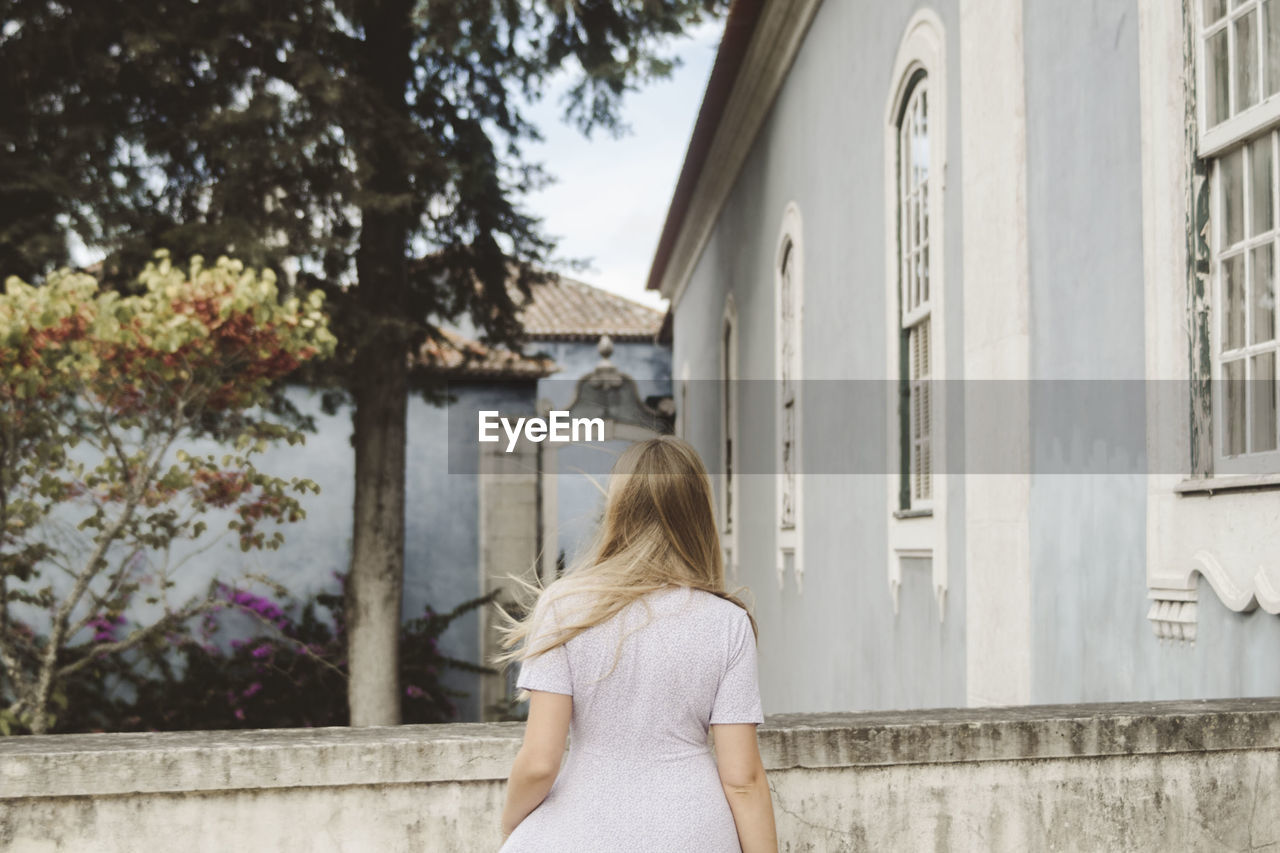 Rear view of woman standing by building