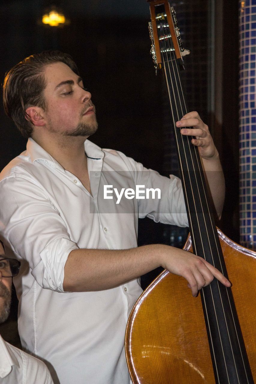 MIDSECTION OF MAN PLAYING GUITAR AT MUSIC CONCERT