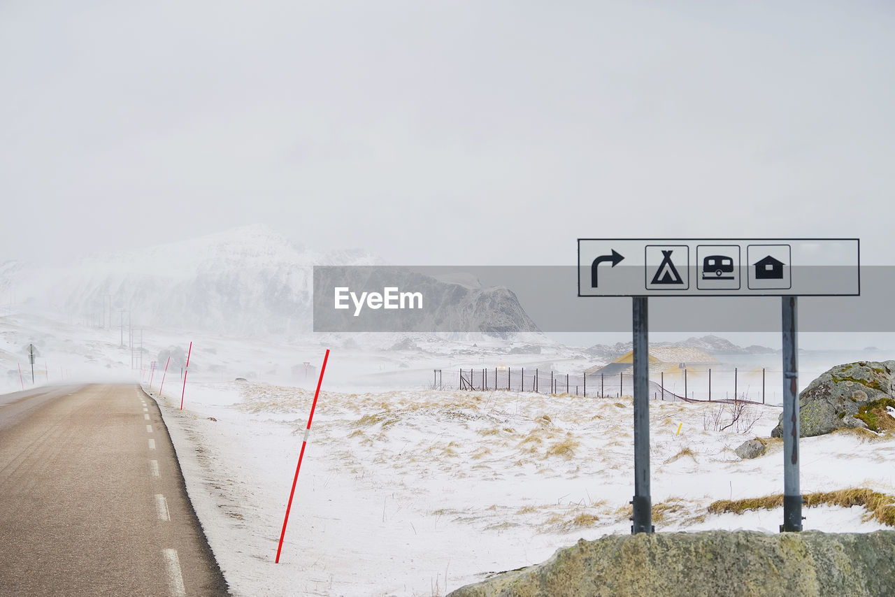 ROAD SIGN ON SNOWCAPPED MOUNTAIN AGAINST SKY