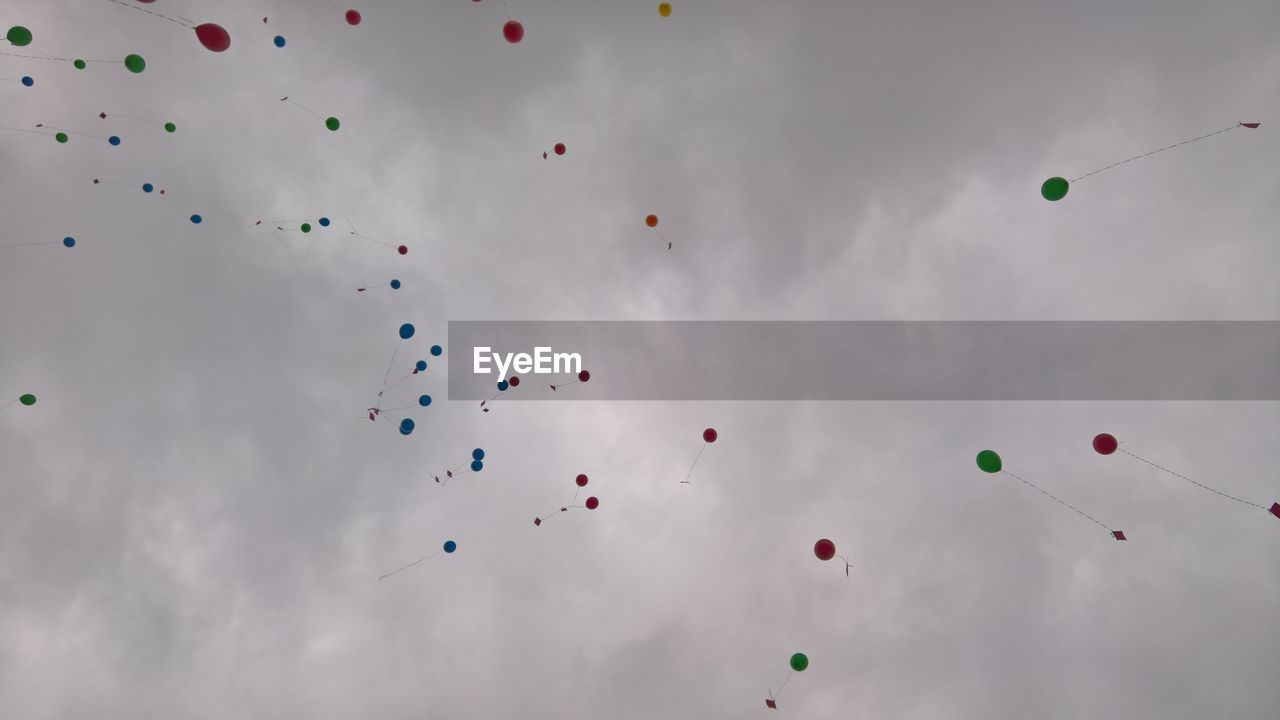 LOW ANGLE VIEW OF MULTI COLORED BALLOONS FLYING AGAINST SKY