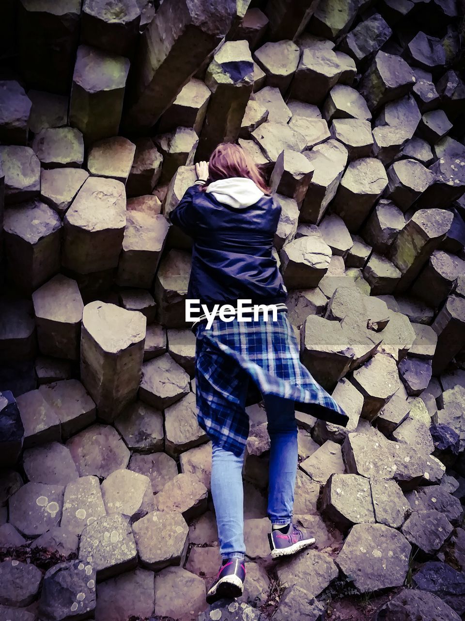 Rear view of girl climbing on rock formation