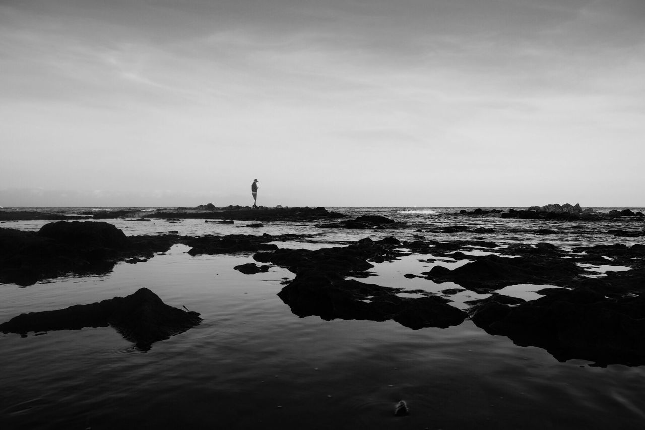 Man standing at beach against sky