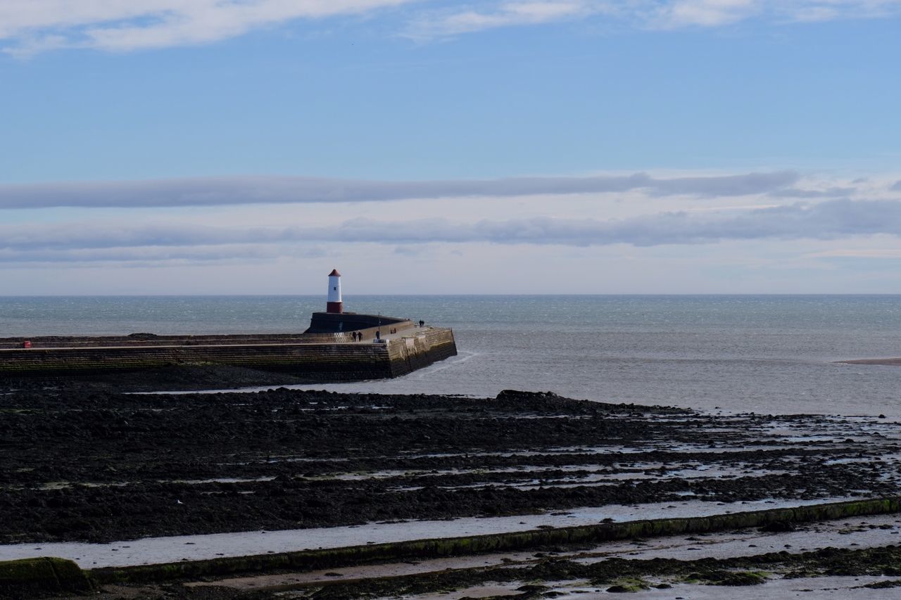 Lighthouse by sea against sky