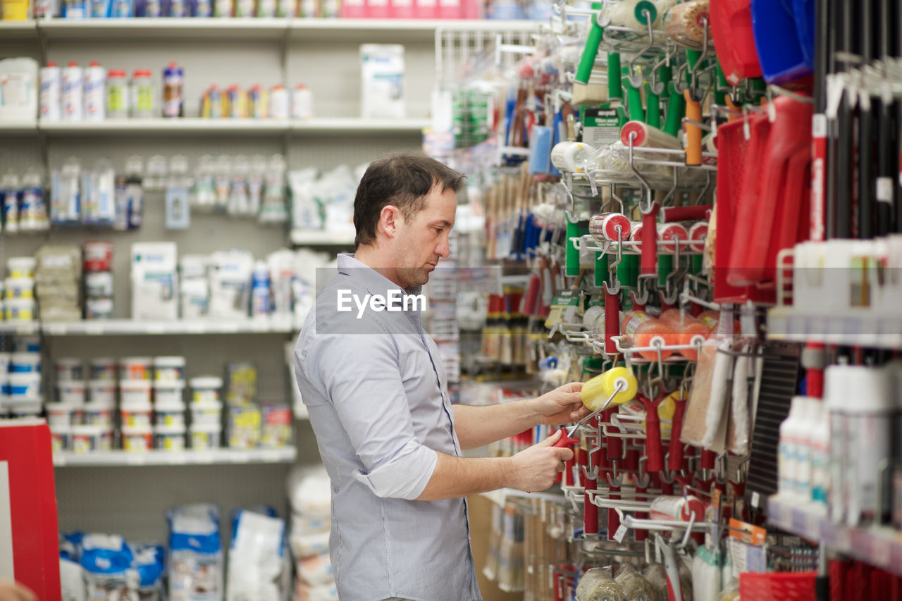 Side view of man buying paint roller in store