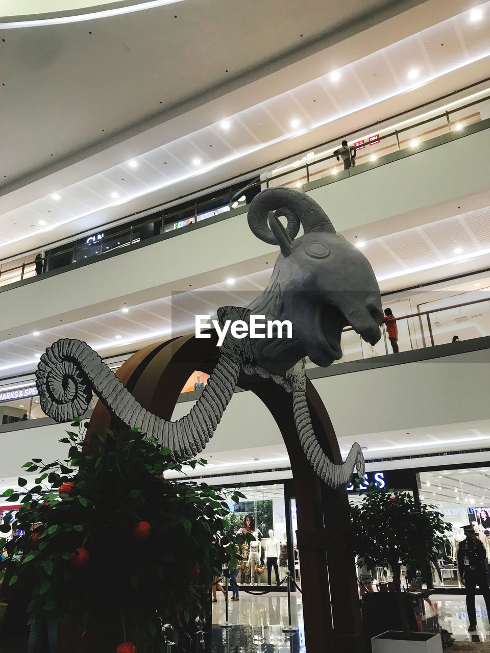 architecture, low angle view, indoors, statue, representation, built structure, shopping mall, person, animal representation, dinosaur, building, clothing