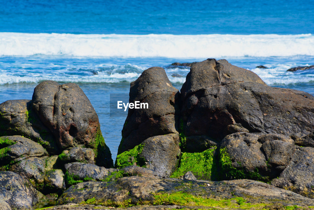 Scenic view of rocks on beach against sky