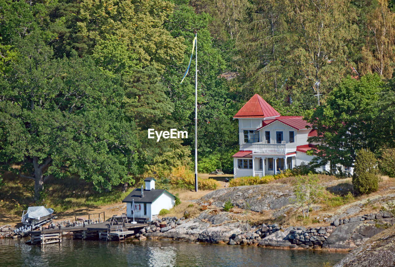 HOUSES BY RIVER AGAINST TREES AND PLANTS