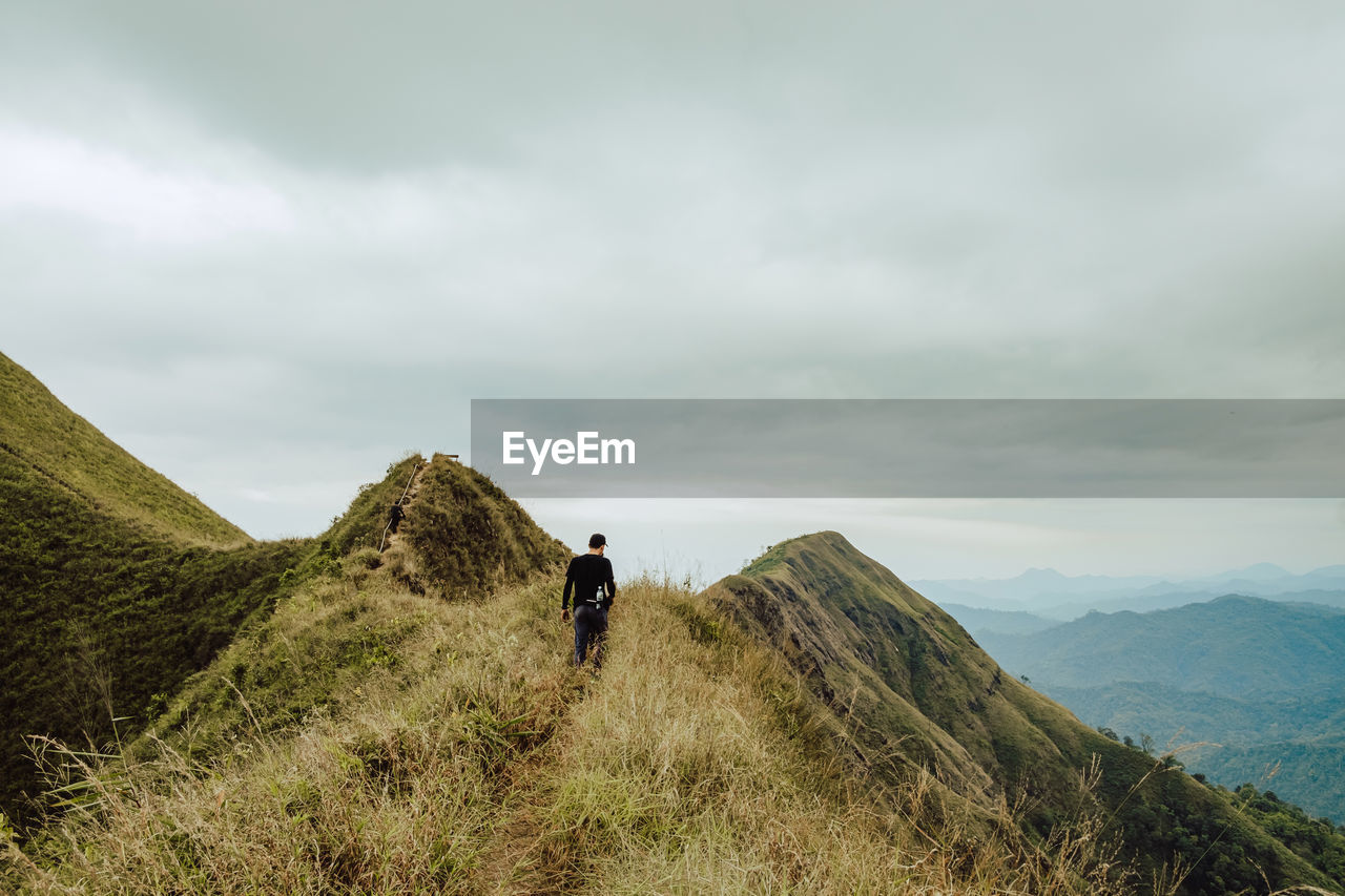 FULL LENGTH REAR VIEW OF MAN ON MOUNTAIN AGAINST SKY