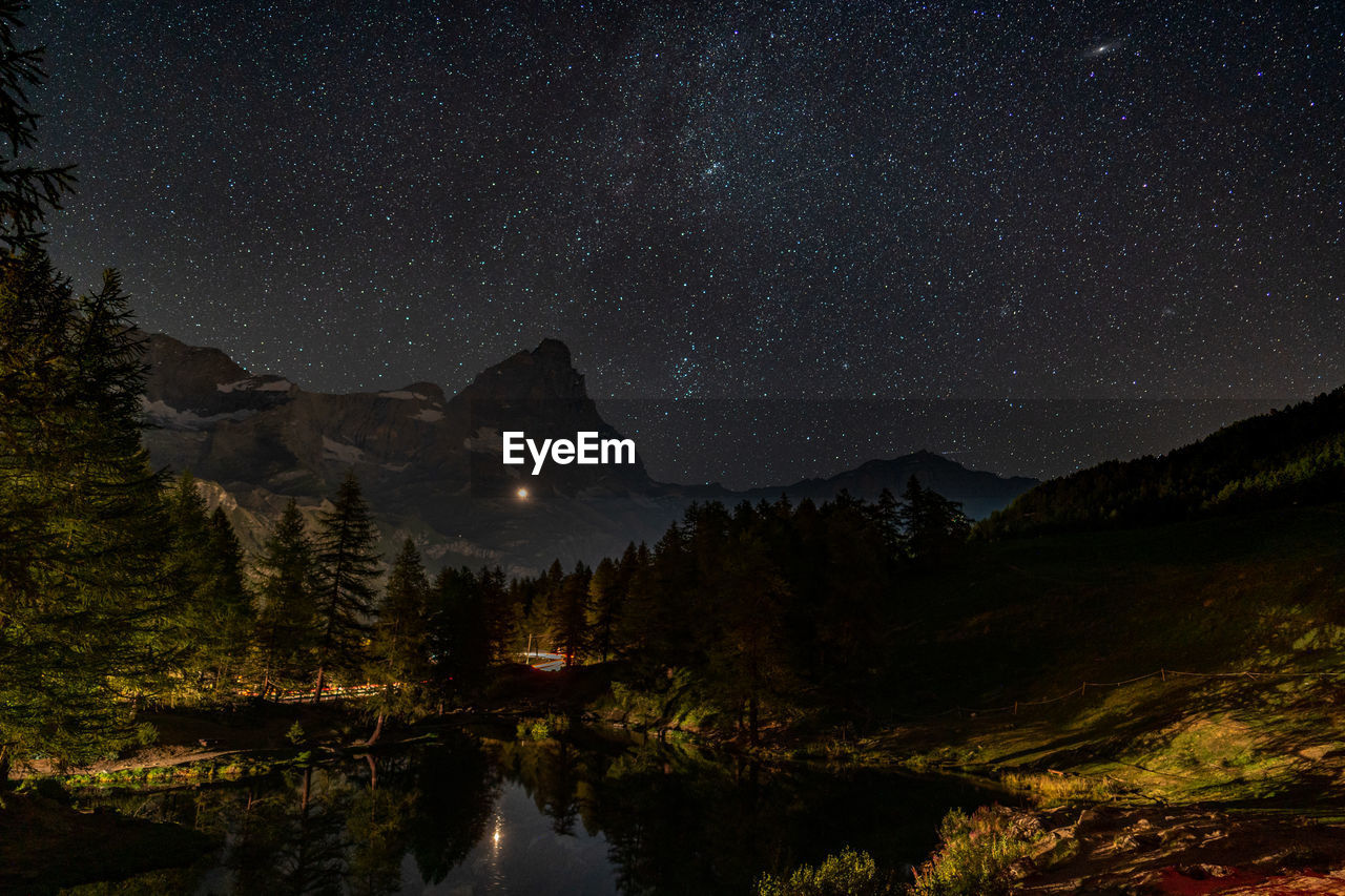 Scenic view of lake and matterhorn against sky at night