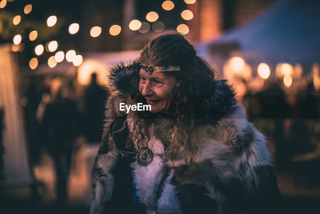 Mature woman wearing fur coat at night