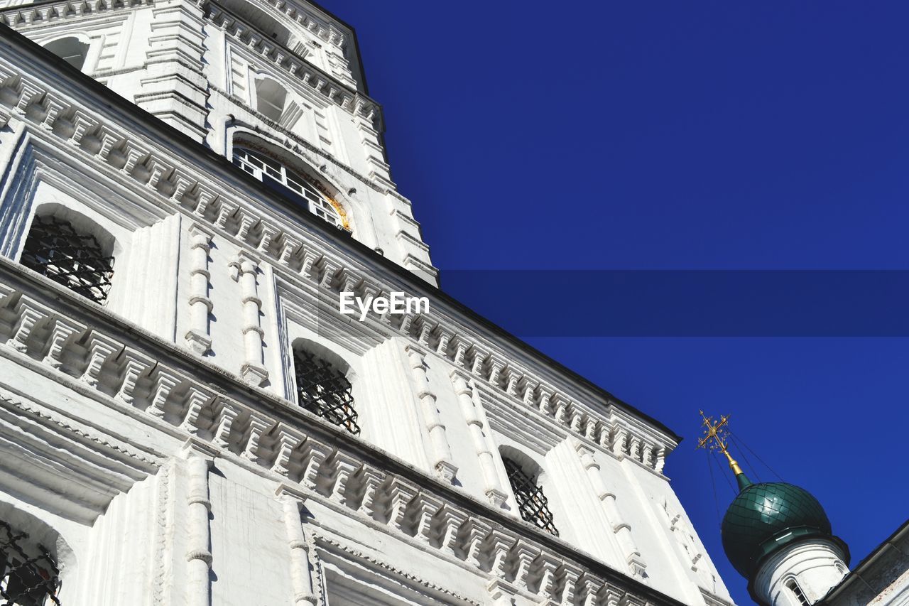 Low angle view of buildings and church against clear blue sky