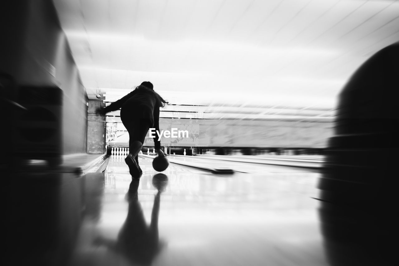 Rear view of woman bowling in alley