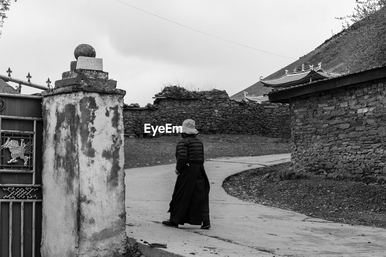 REAR VIEW OF WOMAN STANDING AGAINST BUILDINGS