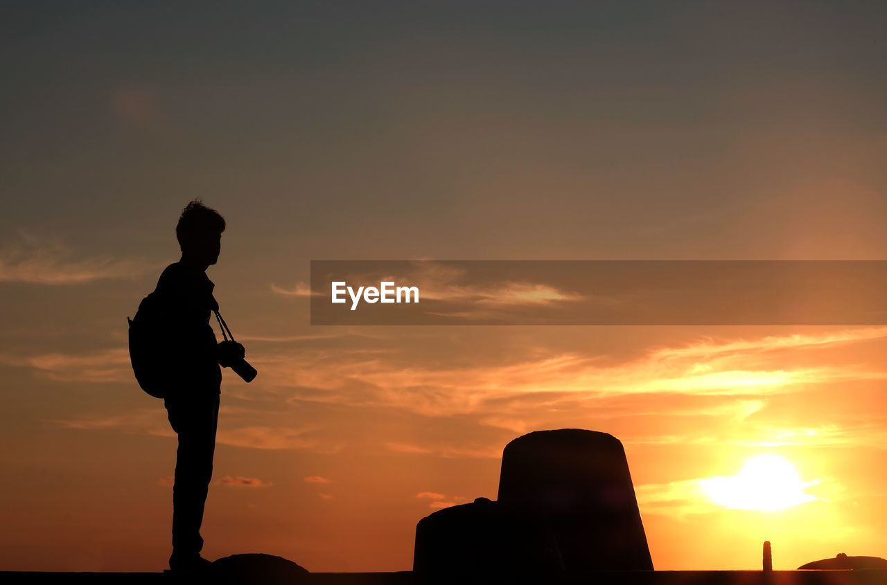 Silhouette man standing against sky during sunset