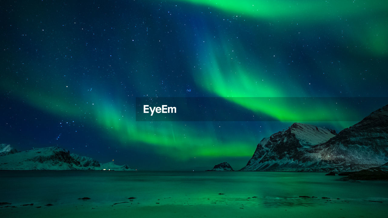 Aurora borealis over sea against sky at night