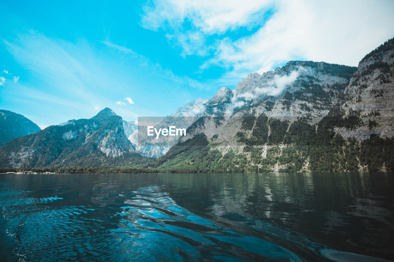 Scenic view of lake and mountains against blue sky